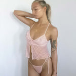 Woman wearing a pink polka dot lingerie set against a white background